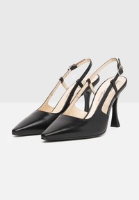 Talons hauts en cuir noir à lanière avec un bout pointu, une fine sangle de cheville et un talon block élevé. L'intérieur présente un revêtement beige contrastant.