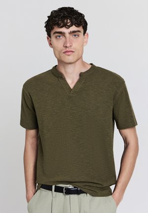 Olivgrünes Kurzarm-T-Shirt aus strukturiertem Stoff, mit Rundhalsausschnitt und legerem Schnitt. Glatte Oberfläche mit subtilen Variationen.