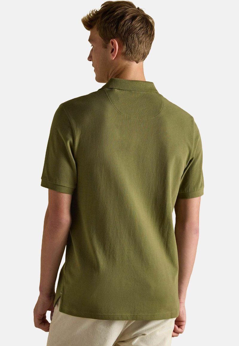 Olivgrünes Poloshirt mit kurzen Ärmeln, Kragen, seitlichen Schlitzen und einer weichen Textur. Einfaches Design, keine sichtbaren Logos oder Muster.