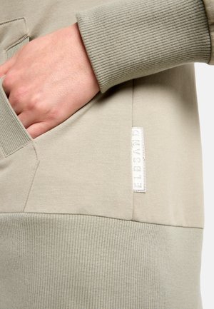 Hellgrauer Pullover mit gerippten Bündchen und einer Fronttasche. Verfügt über eine strukturierte Oberfläche und ein kleines gewebtes Etikett mit dem "ELBSAND"-Logo.