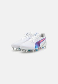 Botas de fútbol blancas con un diseño elegante, que presentan una franja en degradado de color rosa a azul, superficie texturizada y tacos de plástico para mejor tracción.