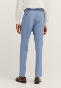 Helleblaue maßgeschneiderte Hosen aus strukturiertem Stoff, schmaler Schnitt, zwei Gesäßtaschen mit Knöpfen und vorderer Faltenlegung für einen eleganten Look.