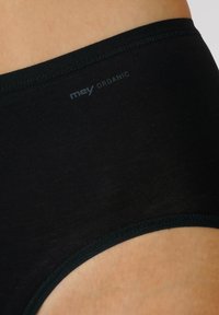 Černé bio bavlněné kalhotky s hladkým povrchem, vybavené jemným pasem a diskrétním logem nahoře. Žádné další vzory ani akcenty.