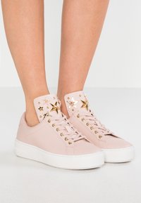 Sneakers in pelle rosa chiaro con suola bianca, caratterizzati da un linguetta decorata con stelle e dettagli in hardware color oro.