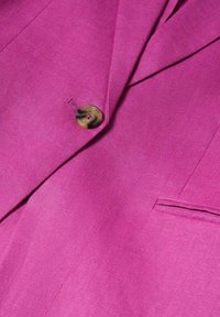 Blazer fuchsia en tissu texturé ; présente un bouton unique avec un design marbré brun et un détail de poche sur le côté.