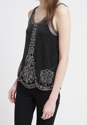 Musta hihaton pusero, jossa pystysuorat helmikoristeet, kukkakoristeet helmassa ja läpikuultavat yksityiskohdat hartioissa, joissa on aaltoileva reunus.