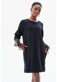 Schwarzes Kleid aus weichem Stoff mit langen Ärmeln, das Tüllakzente aufweist. Das Design hat einen runden Ausschnitt und seitliche Taschen. Einfarbig.