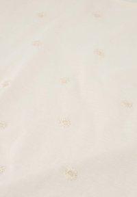 Witte stof met kleine, delicate bloemmotieven, geborduurd met lichte draden, wat een subtiele textuur over het oppervlak creëert.