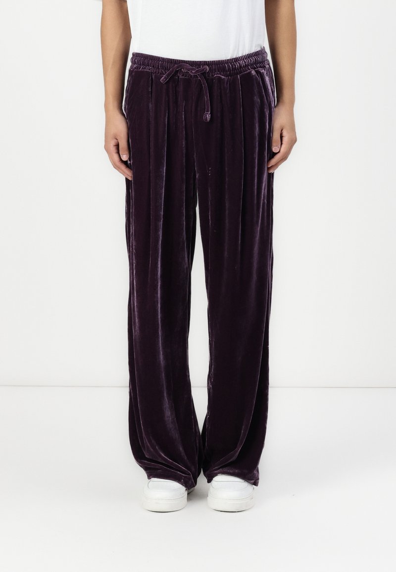 Sammet, vida lila byxor med elastisk midja och dragsko, med en mjuk textur och en lätt glansig yta.