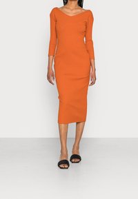 Robe midi orange à rayures avec décolleté en V et manches trois-quarts, associée à des sandales noires à enfiler tressées. Texture lisse, design ajusté.