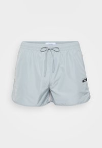 Lichtgrijze zwembroek van synthetisch materiaal met een elastische tailleband, verstelbare trekkoord en zijzakken. Voorzien van een logo patch.