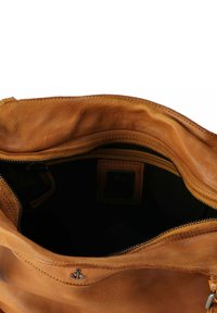 Interno di una borsa a tracolla in pelle marrone con una texture morbida, chiusura con zip e un sottile dettaglio ad ancora. Fodera scura visibile sul fondo.