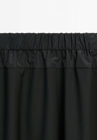 Tessuto di tenda nero con una parte superiore arricciata ed elasticizzata. Texture liscia e colore uniforme, progettato per la privacy e la filtrazione della luce.