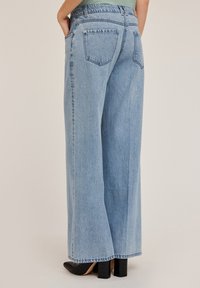 Laajahihteiset, vaaleansiniset farkut, joissa on korkea vyötärö, kaksi takataskua ja raakareuna. Kangas on pehmeää ja hieman haalistunutta.