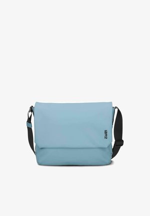 Sac messager bleu clair avec une sangle d'épaule noire réglable et un petit logo vertical sur le côté droit du rabat avant.