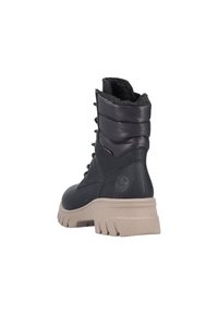 Stivaletti neri in pelle con fodera in pelliccia sintetica, collo a costine e suola beige spessa; dettaglio dei lacci e accentuazione del logo sul lato.