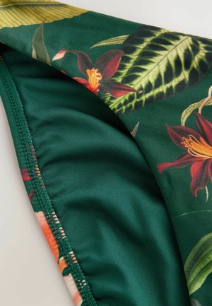 Grøn badetøjsstof med et blomsterprint i røde og orange blomster, omgivet af grønne blade, med en glat tekstur og syede kanter.
