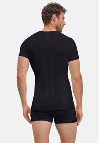 Czarna sportowa bluzka z krótkim rękawem, z teksturowanymi detalami i dopasowanym krojem, zestawiona z czarnymi szortami.