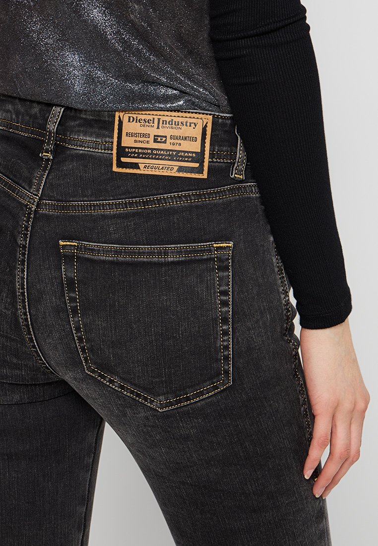 I jeans in denim nero presentano un'etichetta in pelle con il marchio "Diesel Industry", cuciture gialle e tasche posteriori prominenti.