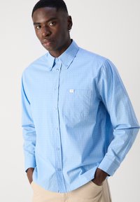 Lichtblauw button-up overhemd met een ruitpatroon, lange mouwen en een borstzak. Gemaakt van gladde stof met een standaardkraag.