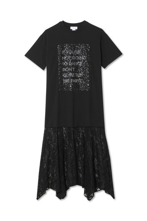 Melna kleita ar īsām piedurknēm, kuras priekšpusē ir aplikācija ar spīdīgu tekstu, un mežģīņu apakšdaļu ar viļņotu malu.