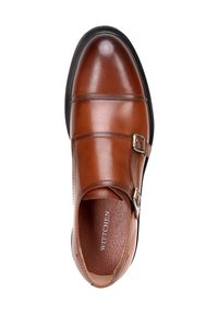 Bruine leren schoen met een gladde afwerking, dubbele riemen met een metalen gespsluiting, ronde neus en zwarte rubberen zool. Binnenin geperst met de merknaam.