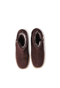 Stivali alla caviglia in suede marrone con un morbido rivestimento interno peloso, chiusura con zip laterale, suola piatta e design a punta rotonda.