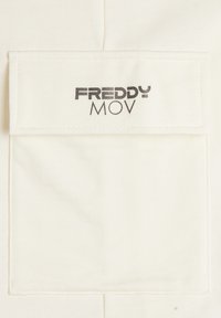 Tissu blanc avec une finition texturée, présentant un patch rectangulaire portant l'inscription "FREDDY MOV" en caractères foncés au centre.