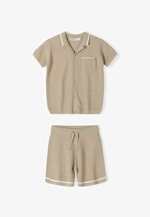 Chemise beige en tricot à manches courtes avec col et poche poitrine, associée à un short assorti en tricot avec cordon de serrage et bordure blanche.