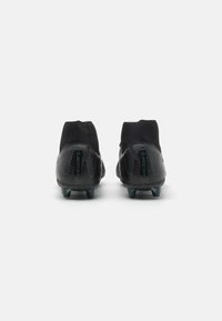 Chaussures de football noires avec une surface texturée, dotées d'un design de cheville type chaussette et d'un talon renforcé, équipées de crampons en plastique pour une meilleure traction.