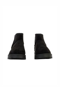 Stivali alla caviglia in suede nero con punta rotonda, suola in gomma nera a profilo basso e design senza cuciture. Presentano una texture liscia e dettagli minimi.