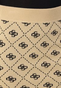 Pull en maille avec un fond beige, motif en losanges noirs et motifs floraux, col côtelé et texture douce.