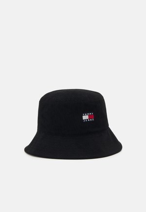 Schwarzer Cordhut im Bucket-Style mit flachem Oberteil, breiter Krempe und gesticktem "TOMMY JEANS"-Logo in Rot, Weiß und Blau.