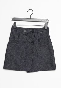 Jupe en tweed gris avec une forme évasée, deux poches avant et une fermeture à double bouton, suspendue à un cintre en métal noir.