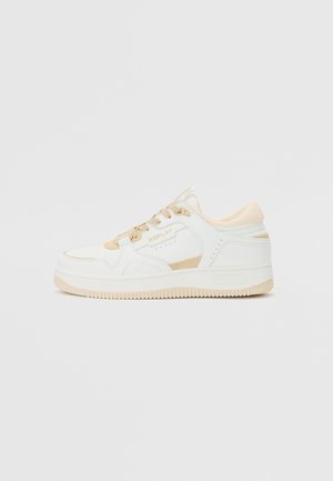 Baskets basses blanches avec des accents beige, fermeture à lacets et détail de marque "REPLAY" sur le côté et la semelle.