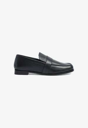 Mocasines de cuero negro con tacón bajo, que presentan un empeine cosido y una banda decorativa a través del empeine. Textura suave, diseño clásico.