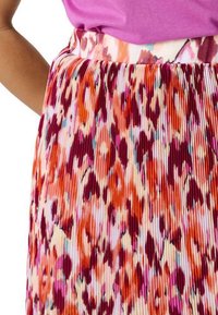 Plissé rok met een kleurrijk patroon van rood, oranje en roze, voorzien van een soepele tailleband, gemaakt van lichtgewicht stof.