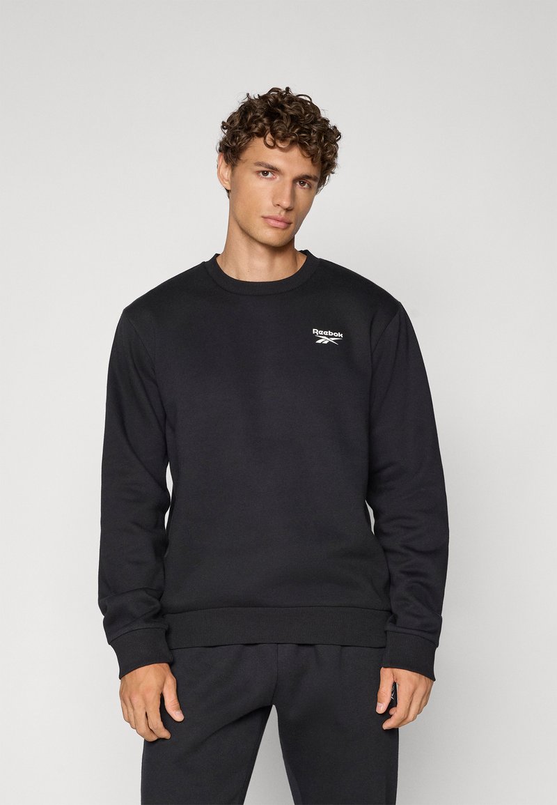 Czarna bluza z bawełnianej mieszanki, z okrągłym dekoltem, prążkowanymi mankietami i dołem, z małym białym logo Reebok na klatce piersiowej.