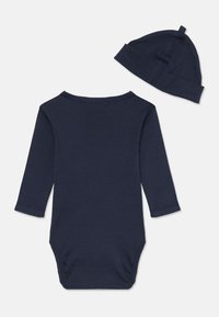 Bodysuit en coton bleu marine à manches longues avec un col rond et un système de fermeture par pression à la base, accompagné d'un bonnet assorti.