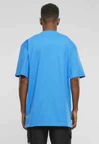 Zila, īsām piedurknēm T-krekls ar apaļu kakla izgriezumu un brīvu piegriezumu, izgatavots no mīkstas kokvilnas, ar gludu tekstūru un bez redzamām grafikām.