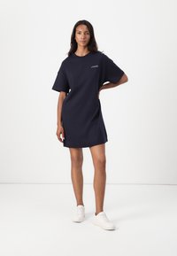 Navyblaues, übergroßes T-Shirt-Kleid aus Baumwolle mit kurzen Ärmeln, rundem Ausschnitt und dezentem Logo-Detail auf der Brust.
