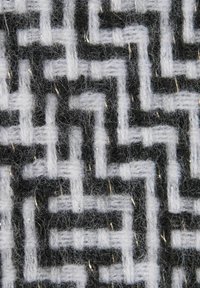 Tessuto intrecciato con un motivo geometrico in bianco e nero con accenti metallici, che presenta un aspetto morbido e testurizzato.