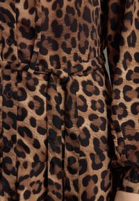 Leopardmönstrad skjorta i brunt och svart, med knytning i midjan, knappslå och strukturerad tyg med slät yta.