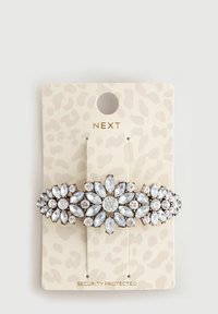 Clemă de păr cu ton de aur, decorată cu trei clustere florale din cristale clare în formă de marquise și rotunde, pe un carton cu imprimeu de leopard bej.