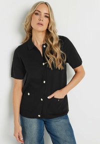 Svart kortärmad skjorta med knappar i mjukt tyg, med två framfickor, knappar i guldton och en klassisk kragsdesign.