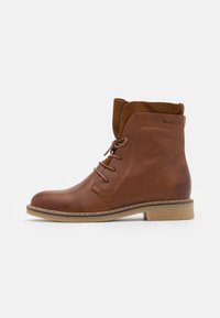 Brune lær ankle boots med snørebånd, en avrundet tå og en myk brune suedekant. Strukturert overflate og lett, naturfarget såle.