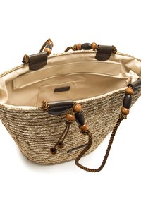Bolso tote de paja tejida con acabado natural, detalles en cuero marrón y cuentas de madera decorativas en las asas. Interior de tela color crema.
