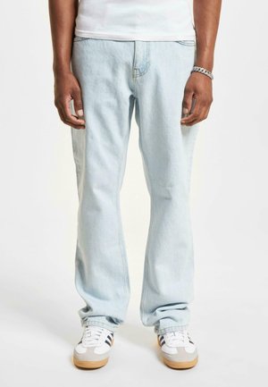 Lysblå denimjeans med lige ben, der har synlige sømme og en subtil vask, parret med hvide sneakers.