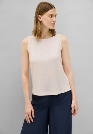 Haut sans manches beige, texture côtelée, col rond, associé à un pantalon large bleu marine. Design simple, tissu léger, sans accents supplémentaires.