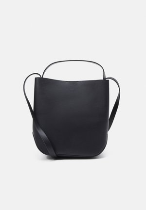 Bolso tipo cubo de cuero negro con dos asas finas y una superficie lisa y estructurada sobre un fondo blanco liso.